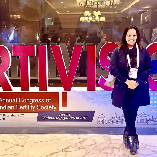 A woman standing in front of a large conference sign reading FERTIVISION, 19th Annual Congress of the Indian Fertility Society, 2023.